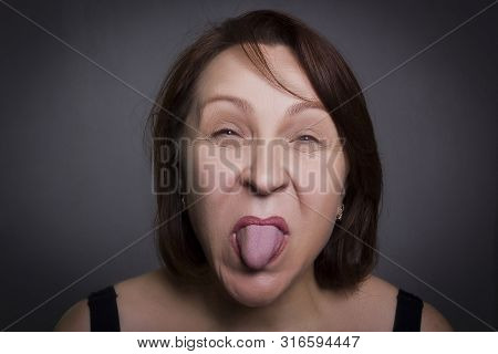 Woman Grimaces In Front Of Camera On Black Background