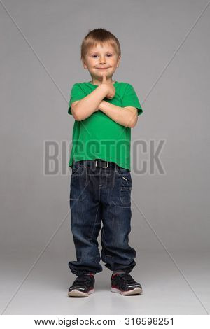 Portrait of happy smiling boy in green t-shirt and jeans. Attractive kid in studio.