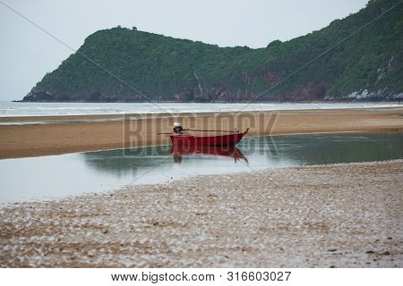 An Old Red Fisherman Boat At On The Beach In Cloudy Day