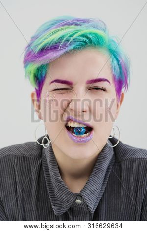 A Young Woman With Short Pixie Bob Haircut And Dyed Hair, Holds In The Mouth And In The Hands Gemsto