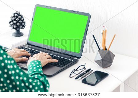 Close-up Of Hands Middle-aged Woman Typing On Keyboard Green Screen Laptop, Concrete Holder With Pen