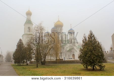 Five-domed White Church With Blue And Gold Domes Behind Bare Trees In The Morning Fog