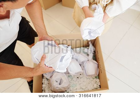 People Taking Glasses Wrapper In Paper Out Of Carboard Box With Protective Polystyrine Chips
