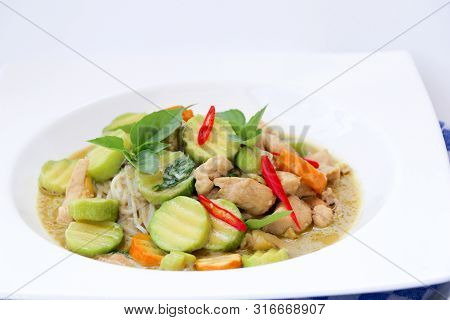 Close Up Of Green Curry With Chicken And Green, Yellow Zucchinis Served With Thai Noodles And Red Ch