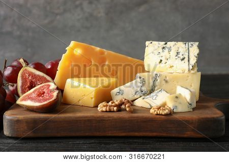 Different Delicious Cheeses Served On Wooden Board