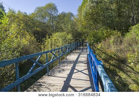 A Wooden Pedestrian Bridge In A Small Ravine. Early Autumn, Sunny Day In September. Landscape Reserv
