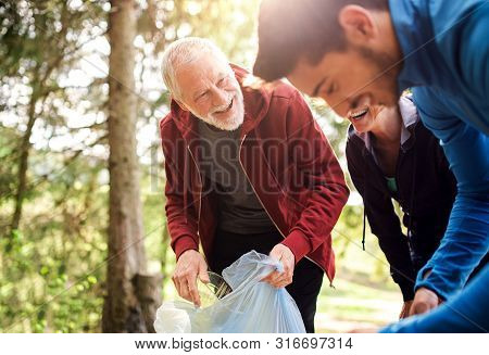 Group Of Active People Picking Up Litter In Nature, A Plogging Concept.