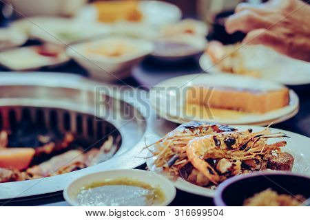 People Grilling Meat On A Smokeless Barbecue Grill In A Restaurant. Selective Focus On Shrimps.