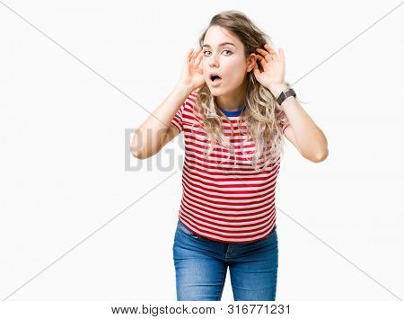 Beautiful young blonde woman over isolated background Trying to hear both hands on ear gesture, curious for gossip. Hearing problem, deaf