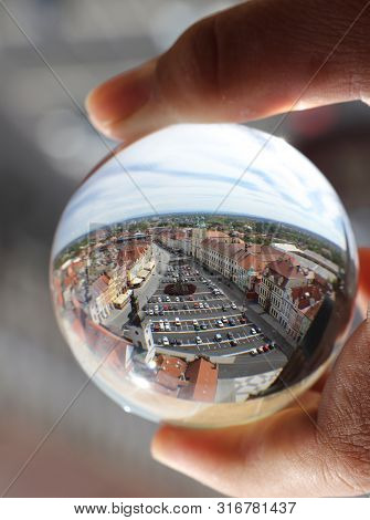 Market Square Of Hradec Kralove In Lens Ball Which Photographer Is Holding In Fingers. Crystal Ball 