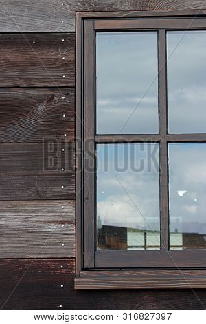Large Window On A Wooden Building Reflecting The Sky On A Cloudy Overcast Day
