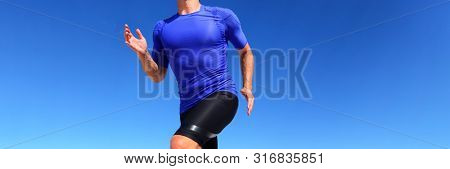 Sport runner male athlete running in compression sportswear clothing outdoor on blue background. Panoramic banner of man on run race.