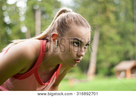 Young Woman Is Out Of Breath And Makes A Breather Bent Over While Doing Sports Outdoors