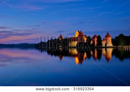 Trakai Island Castle in lake Galve, Lithuania on sunset with dramatic sky reflecting in water. Trakai Castle is one of major tourist attractions of Lituania
