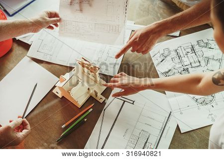 Top View Of Achitect-engineers Hands Shows Future House, Office Or Store Design Plans To A Young Cou