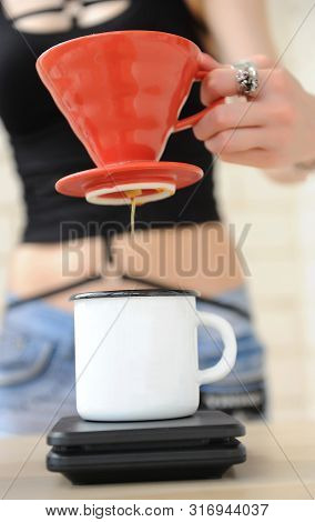 Girl Barista Brews Coffee In Red V60 Pourover. Dripping Water From Funnel In Hand Into White Cup On 