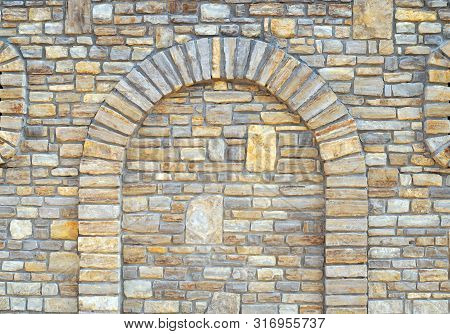Stone Wall Background With Arch. Walled-up Archway In A Stone Wall Background.