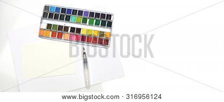 White box with watercolors and brush on white background. Flat lay. Top view.. Horizontal long  Template for posters, greeting cards, web site, banner, invitation.