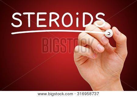 Hand Writing Word Steroids With White Marker On Transparent Wipe Board On Dark Red Background.