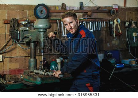 A Mechanic Drills A Detail On A Drill Press. Workflow Mechanic In A Car Garage. Auto Service Concept