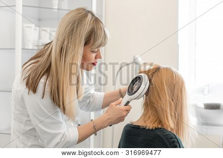 The Doctor Trichologist Dermatologist Examines The Scalp And The Patient's Hair Condition With A Der