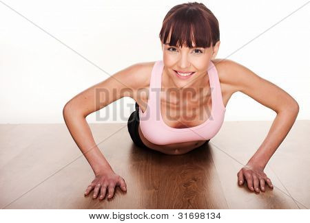 Happy young Woman looking at die Kamera auf ihre Hände auf einem Holzfußboden auferweckt zu u drücken