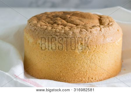 Tall, Ruddy Sponge Cake On A White Towel With A Red Stripe