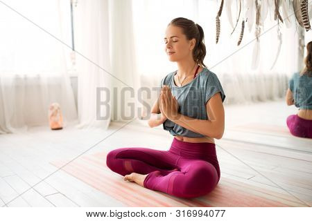 mindfulness, spirituality and healthy lifestyle concept - woman meditating in lotus pose at yoga studio