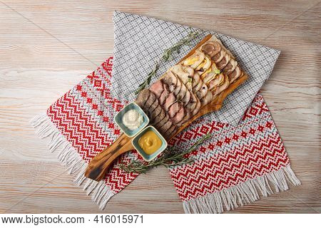 Set of chicken roll, pork meatloaf, beef, saltison and chicken pate on wooden tray in restaurant. Top view.