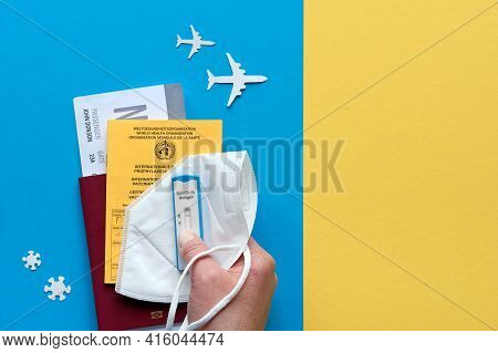New Normal Travel During Covid-19 Restrictions, Flat Lay On Blue Yellow Paper. Hand Hold German Pass