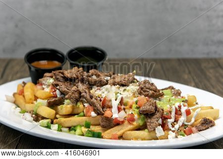 Large Plate Of Asada French Fries Covered In Cheese Served With Dipping Sauce Will Tempt Everyone.