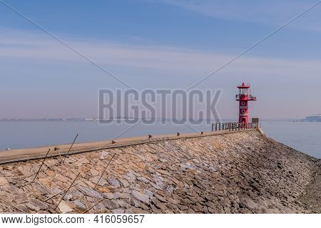 Red Lighthouse At End Of Concrete And Stone Pier.