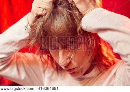 Portrait Of Tousled Disheveled Middle-aged Woman Looking Like A Madwoman On Red Background In Studio