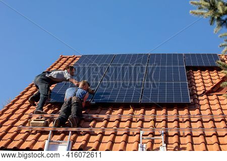 Ochojno, Poland - April 8, 2020: Workers Installing Solar Electric Panels On A House Roof In  Ochojn