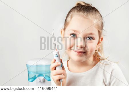 Irrigator. Pretty Girl Child Holds Electric Water Flosser In Her Hands And Smiling.