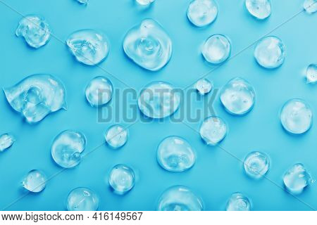Drops Of Gel With Hyaluronic Acid In The Form Of A Smear Of Glossy Texture On A Blue Background.