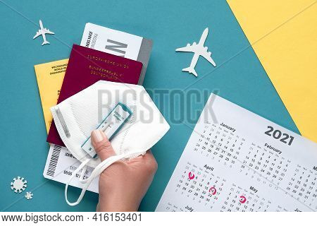 New Normal Travel During Covid-19 Restrictions, Flat Lay On Green And Yellow Paper. Hand Hold German