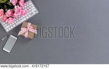 Desktop Workspace With Computer Keyboard, Giftbox, Smartphone And Lovely Pink Rose Flowers In Flat L