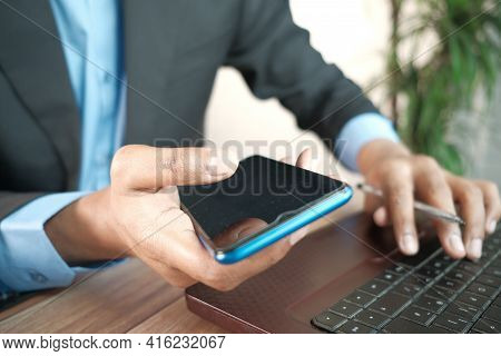 Businessman Hand Using Smart Phone And Typing On Laptop