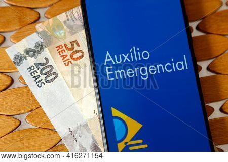 Minas Gerais, Brazil - April 6, 2021: Auxilio Emergencial In Mobile Phone Application And Money Bill