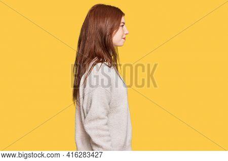 Young read head woman wearing casual winter sweater looking to side, relax profile pose with natural face with confident smile. 