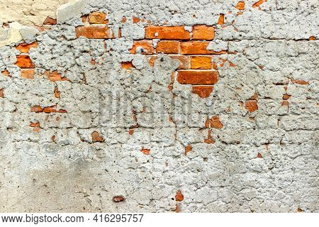 An Old Damaged Brick Wall Partially Covered With Old Cracked Plasterwork As A Background