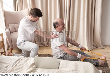 Male Yoga Trainer Helps To Senior Man To Do Asana Correctly.