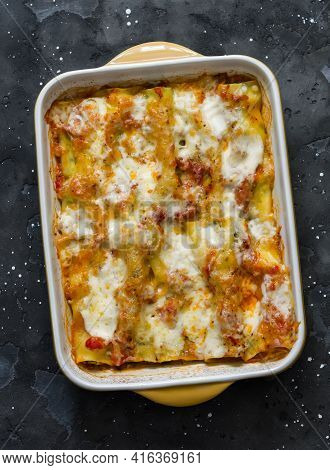 Cannelloni With Spinach And Ricotta Baked With Mozzarella In A Baking Dish On A Dark Background, Top