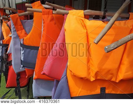 Colorful Water Life Vest. Life Jackets Hanging On Clothes Line. Buoyancy Jackets On A Rail. Water Sp