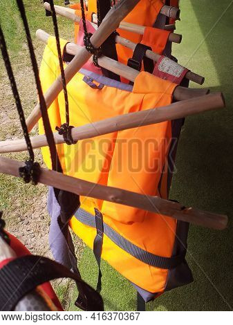Life Jackets For Buoyancy Hung On Rustic Wooden Hangers. Water Sports Safety Accessory. Sports Equip