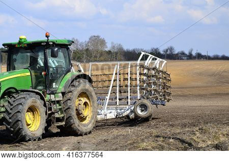A Large Modern John Deere Tractor Tows A Cultivator In A Field