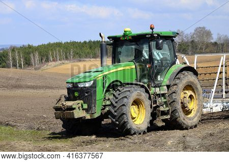 A Large Modern John Deere Tractor Tows A Cultivator In A Field