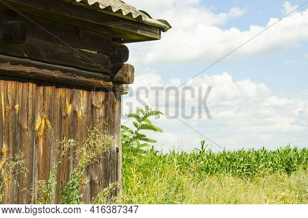 A Corner Of An Old House Overlooking An Overgrown Abandoned Field. Summer Landscape. Traditional Cot