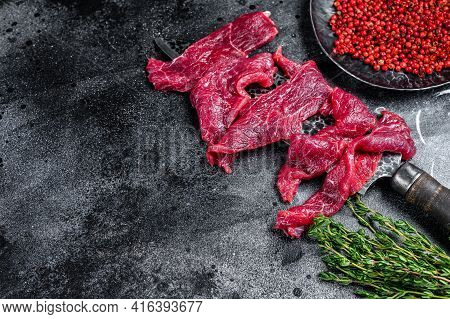 Raw Marbled Meat Cut Into Thin Strips For Beefstroganoff. Black Background. Top View. Copy Space